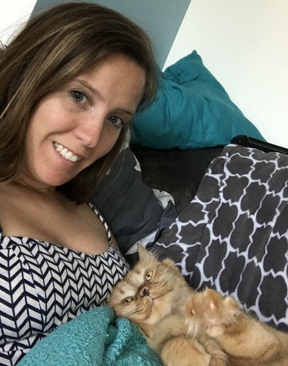 an orange cat laying with her human