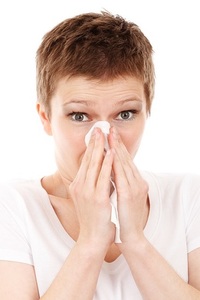 a woman blowing her nose from allergies